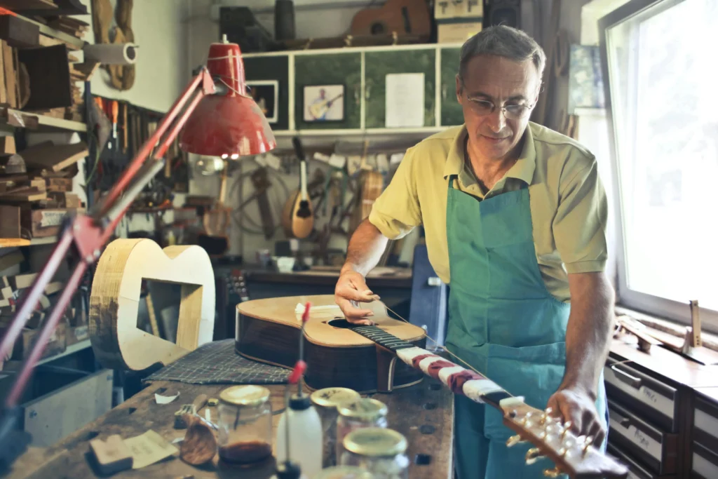a guitar luthier mending a guitar in his workshop