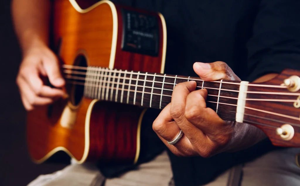 hands playing an acoustic guitar.